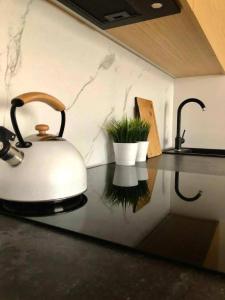 a kitchen counter with a tea kettle on a table at Apartaments Airport Komputerowa Premium in Warsaw