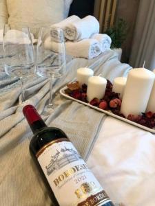 a bottle of wine and candles on a bed at Apartaments Airport Komputerowa Premium in Warsaw