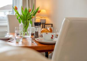 a table with a vase of tulips and a plate of food at Trevelgue in Saint Merryn