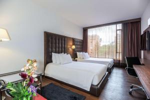 a hotel room with two beds and a large window at NH Collection Bogota Andino Royal in Bogotá