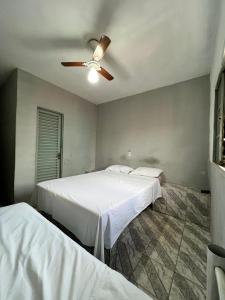 2 camas num quarto com uma ventoinha de tecto em Pousada Sol em Goiânia