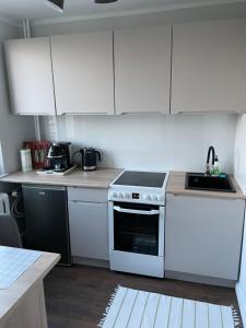 a kitchen with white cabinets and a stove top oven at Harmony Apartament in Suwałki