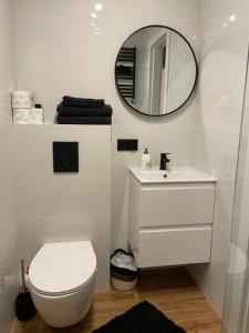 a bathroom with a white toilet and a mirror at Harmony Apartament in Suwałki