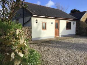 a white cottage with a brown door on a gravel driveway at Tregonning Lodge in Helston