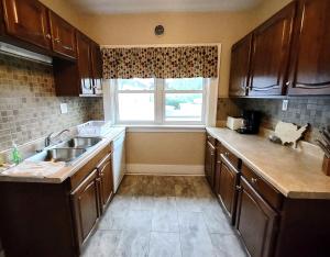 a kitchen with wooden cabinets and a sink and a window at Spacious Frontier Park Apartment in Erie