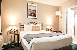 - une chambre avec un grand lit et deux lampes dans l'établissement Sierra Mountain Inn, à Grass Valley