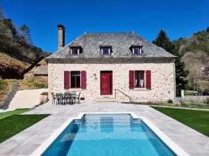 - une vue extérieure sur une maison en pierre avec une piscine dans l'établissement Gîte de France L'air du paradis 3 épis - Gîte de France 6 personnes 344, à Argentat