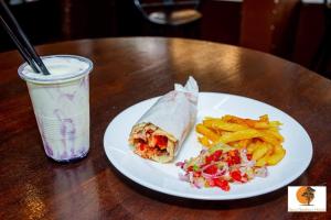 a plate with a sandwich and french fries and a drink at Tana Garden Hotel in Garissa