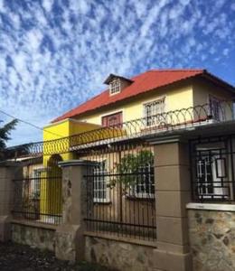 a yellow house with a red roof and a fence at Casa de vacaciones el volcán in Managua