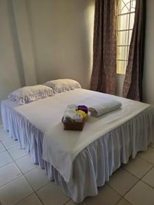 Una cama blanca con toallas y una cesta. en Casa de vacaciones el volcán, en Managua