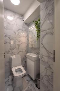 a white bathroom with a toilet and a sink at T20 Apartments in Skopje