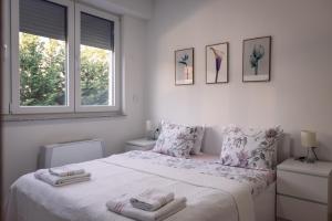 a white bedroom with a bed and two windows at T20 Apartments in Skopje