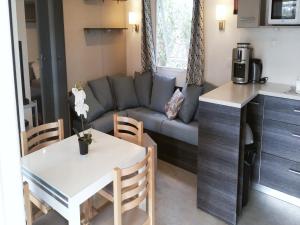 a kitchen and a living room with a couch and a table at mobil home confort premium in Valras-Plage