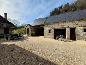 - un bâtiment en pierre avec des tables et des chaises devant dans l'établissement Gîte de France Gîte le petit air 3 épis - Gîte de France 3 personnes 624, à Argentat