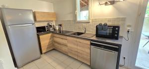 a kitchen with a sink and a refrigerator at Villa dans résidence avec piscine , stationnement proche de la mer in Vendres