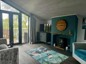 sala de estar con chimenea y reloj en la pared en Stunning 2 Bed Lodge On The Lake, en South Cerney