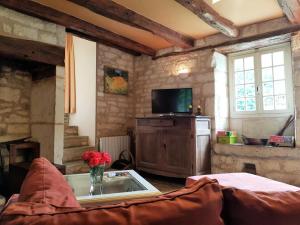 een woonkamer met een tv en een bank bij Gîte de France Combelonge 3 épis - Gîte de France 6 personnes 874 in Turenne