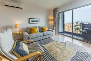 a living room with a couch and a large window at Xenon Urban Apartments in Maputo