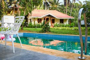 a swimming pool with a chair and a house at White Serenity Heritage Pool Villa near Beach Udupi in Udupi