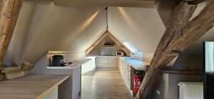 una cocina en el ático con armarios blancos y techo en Guesthouse Bonheure en Bruges