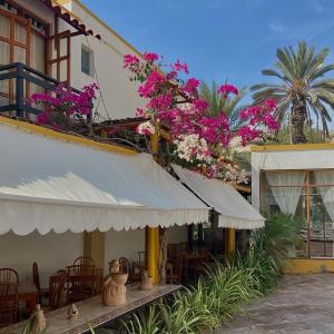 a building with tables and chairs and pink flowers at Hosteria Suiza in Ica