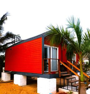 ein rotes Haus am Strand mit Palmen in der Unterkunft Chan Beach Resort & Hotel in Bahūr