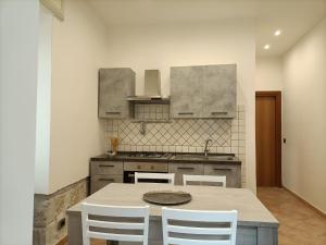 a kitchen with a table and white chairs in it at ALTAMAREA appartamenti sul porto in Pozzuoli +14 photos