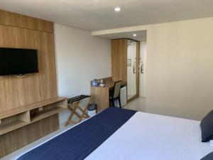 una camera d'albergo con letto e TV di Apartamento Hotel Itaipava Petropolis a Petrópolis