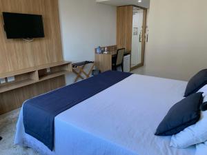 a bedroom with a bed with blue sheets and pillows at Apartamento Hotel Itaipava Petropolis in Petrópolis