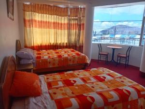 Habitación con 2 camas, mesa y ventana en INKA'S DREAMS HOUSE, en Puno