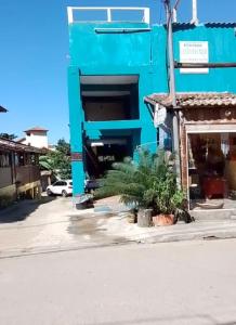 a blue building with a palm tree in front of it at Canto do mar in Paraty
