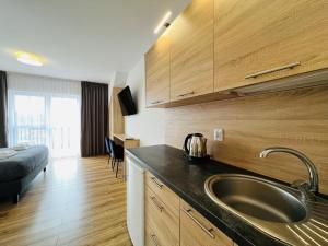 eine Küche mit einem Waschbecken und ein Zimmer mit einem Bett in der Unterkunft ROYAL VILLA - Adults Only - Pokoje z widokiem na Zalew Wiślany-Grupa PlażoweLove in Krynica Morska