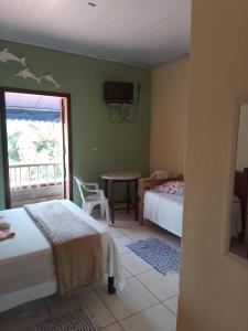 a bedroom with two beds and a table with a balcony at Canto do mar in Paraty