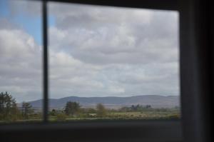 a window view of a field with mountains in the distance at Enniscrone Luxury Double Room in Enniscrone