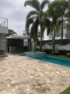 uma piscina em frente a uma casa com palmeiras em Casa alquiler en isla mocoli em Guayaquil