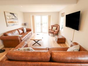 sala de estar con muebles de cuero marrón y TV de pantalla plana. en Foremans Cottage, en Hull