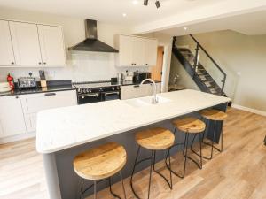 a kitchen with a white counter top and wooden stools at Foremans Cottage in Hull