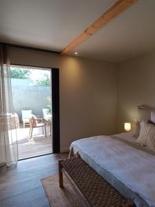 a bedroom with a bed and a sliding glass door at Hôtel Les Suites Du Maquis in Bonifacio