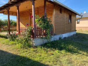 a wooden cabin with a porch with flowers on it at Prenoćište Stupovi in Novi Pazar