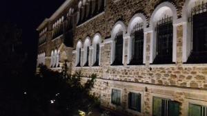 VolissosにあるZorbas Apartmentsの夜間の窓のある大きなレンガ造りの建物