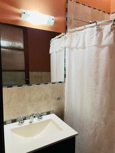 a bathroom with a sink and a white shower curtain at Casona Margarita in Concordia
