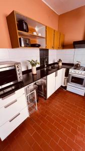 uma cozinha com armários brancos e piso em azulejo vermelho em Casona Margarita em Concordia