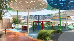 a playground with umbrellas in a park at Skyline Azure - Elegant 2BR Duplex in Oasis Near Masdar Park in Abu Dhabi