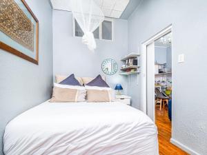 1 dormitorio con 1 cama con sábanas blancas y paredes azules en Cosy Victorian Style Full Apartment, en Ciudad del Cabo