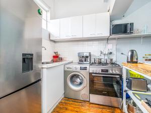 a kitchen with a stove and a washing machine at Cosy Victorian Style Full Apartment in Cape Town