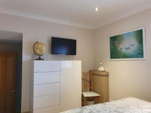 een slaapkamer met een televisie aan de muur en een dressoir bij Maple Cottage B&B in Gullane