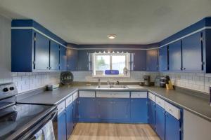 cocina con armarios azules, fregadero y ventana en Albany Family Lake Getaway Near State Parks! en Albany