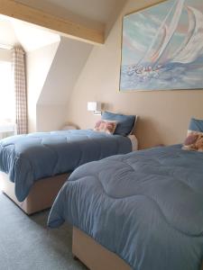 a bedroom with two beds and a painting on the wall at Maple Cottage B&B in Gullane