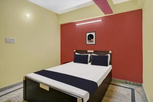 una camera con un letto con una parete rossa di OYO 27 DEGREE HOTEL a Jamshedpur
