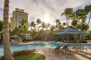 a pool at a resort with chairs and an umbrella at Hyatt Regency Coconut Point Resort & Spa Near Naples in Bonita Springs